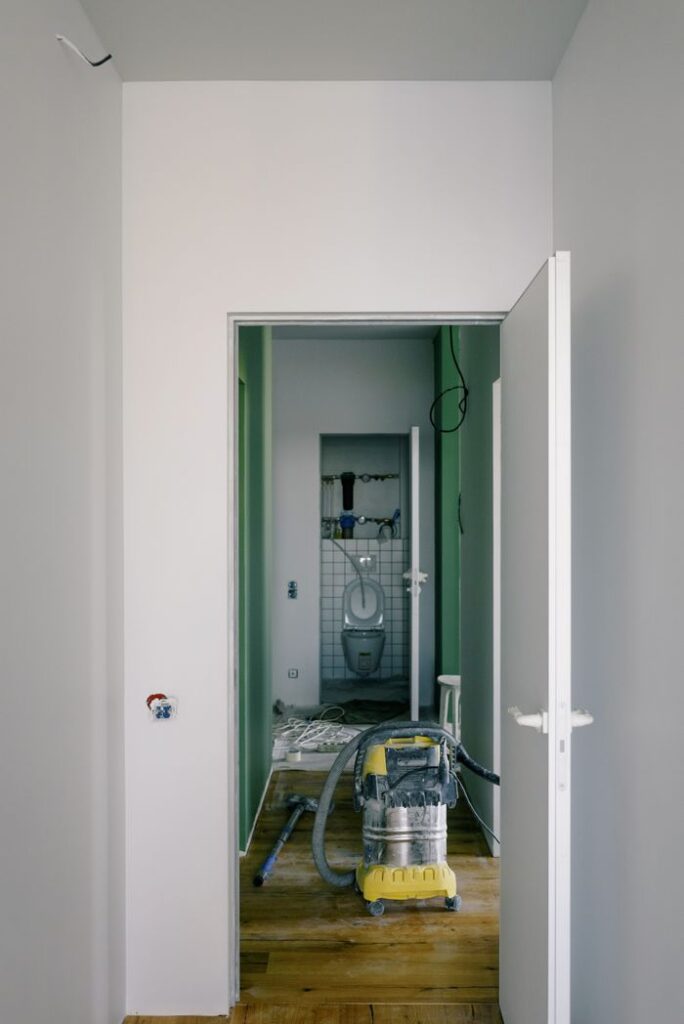 Small dark water closet and vacuum cleaner in hallway in empty apartment in new building